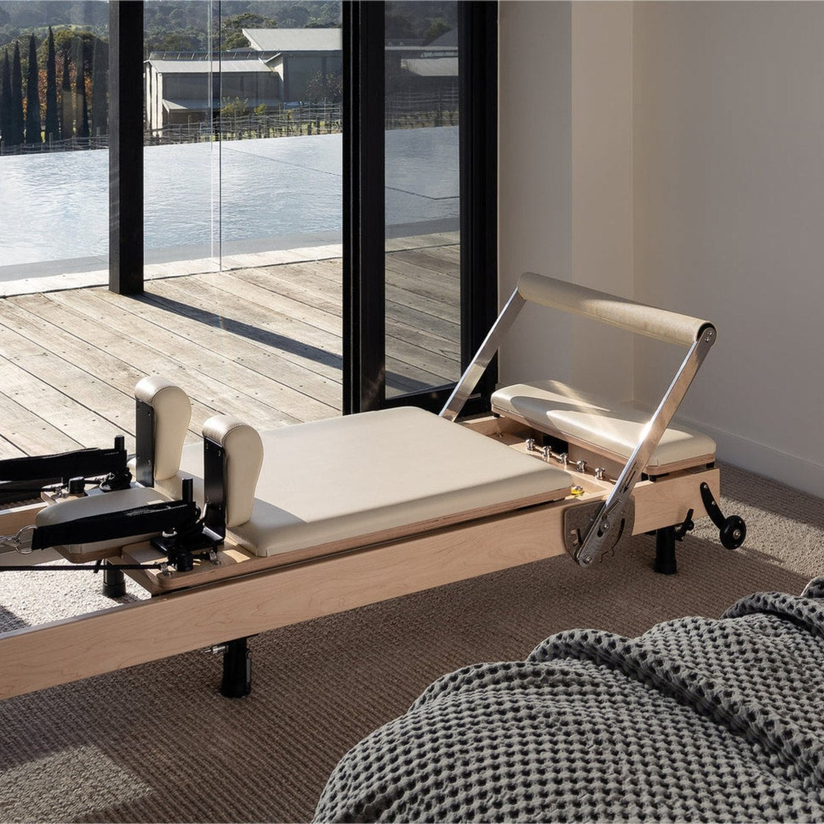The Studio Reformer set up by a window overlooking a deck and pool
