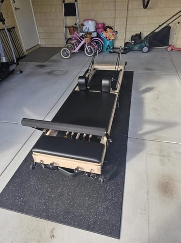 A Studio Reformer on a mat in the garage