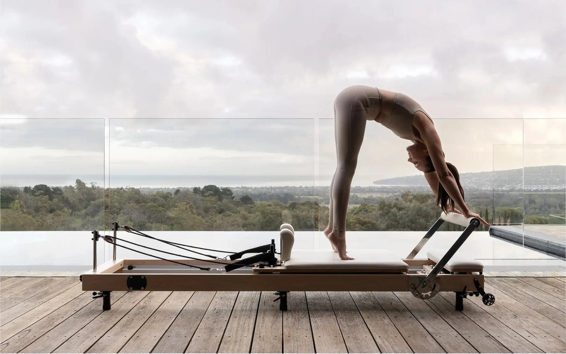 Person doing Pilates on a reformer with a scenic outdoor view.